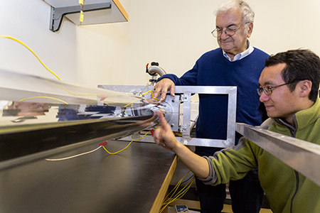 Professor Roland Winston (standing) and postdoctoral researcher Lun Jiang work on a solar collector system.